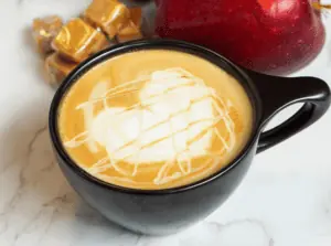 A latte in a black mug with foam set in the shape of a heart.