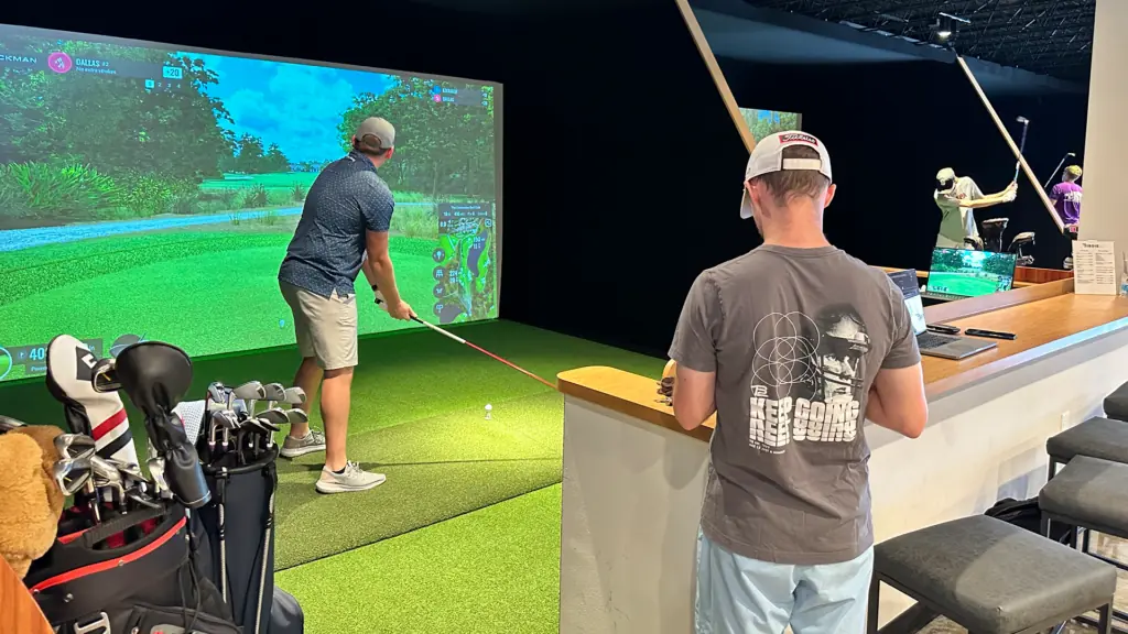 two golfers in a bay playing on a virtual golf course