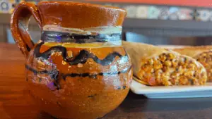 a clay mug next to a breakfast burrito