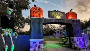 exterior of our haunted trail with a large skeleton next to an archway with two pumpkins on top