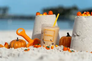 an iced coffee drink in the sand surrounded by sand castles