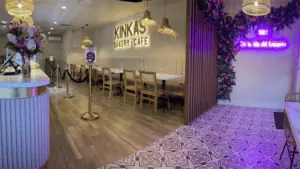 interior of a lit up bakery with neon signs, and a big gold sign that reads "Kinka's"
