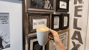 A mug filled with a hot latte held in front of a wall of black and white photos