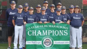 a group of kids in baseball uniforms pose in front of a green Champions banner