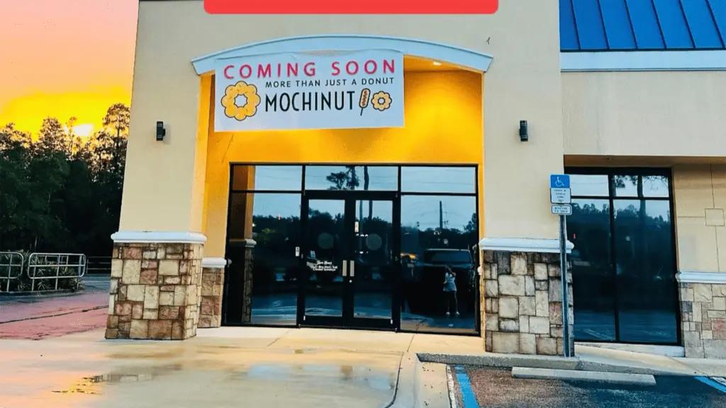 exterior of a donut shop with a large white coming soon banner over the front door