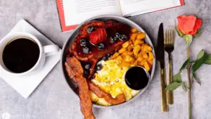 aerial view of French toast covered in berries, with eggs and bacon on the side