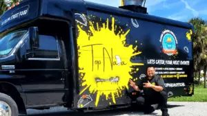 a chef posts in front of a food truck with a black and yellow paint job