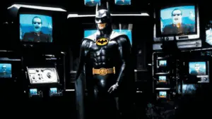 batman stand up in front of multiple screens in the bat cave.