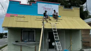 exterior of a Mexican restaurant with two people sitting on a roof painting it blue