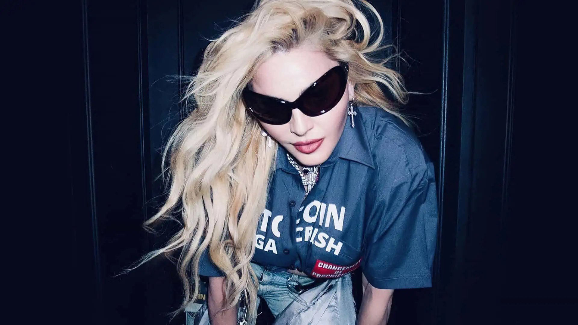 Madonna leans towards the camera with her hair down and wearing oversized sunglasses