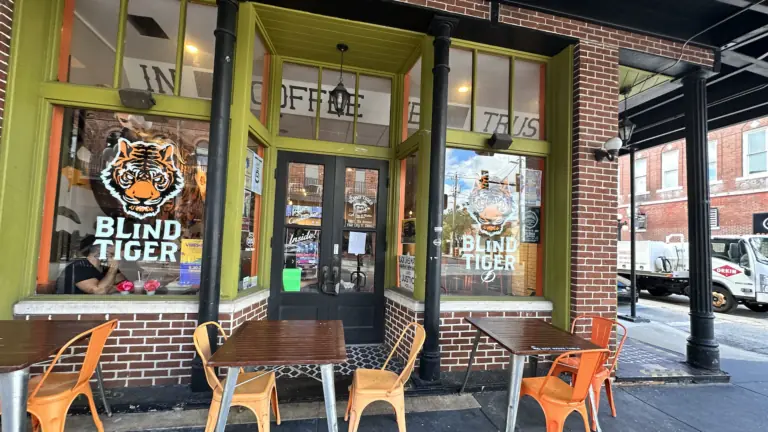 outside a coffee shop with tiger logos on the window and orange chairs arranged around the doors