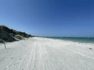 A white sand beach with dunes to the left