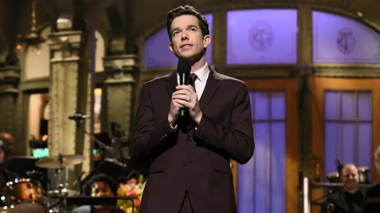 A comedian in a full suit performs stand up on stage at Saturday Night Live.