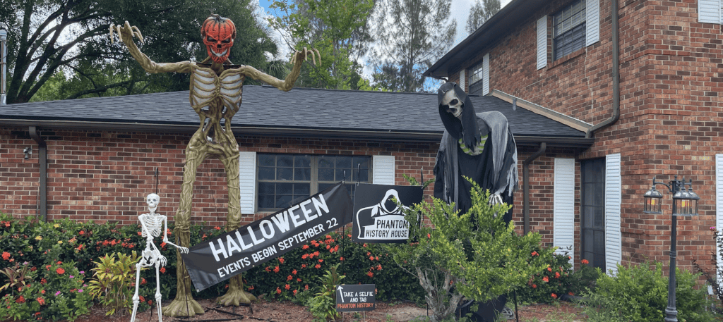 exterior of a house with multiple halloween decorations such as a tall skeleton with a pumpkin head