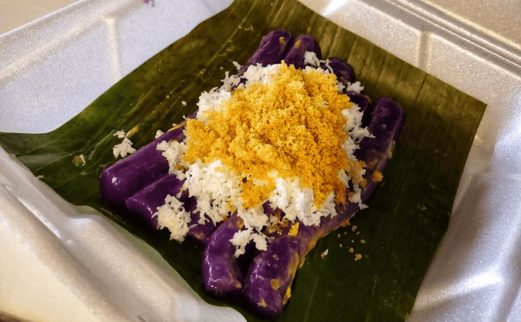 there fried rolled treats on a green ledge covered in ube, coconut, and cheese