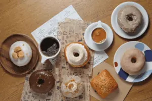 array of frosted donuts next to a cup of coffee