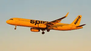 airplane flying in the sky at golden hour. It's a spirit airlines plane with a yellow paint job