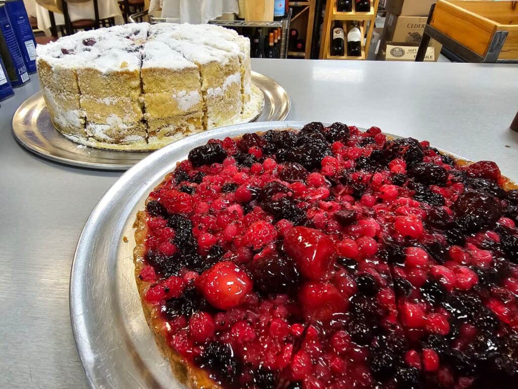 tow large cakes, one topped with vanilla frosting, the other featuring berries