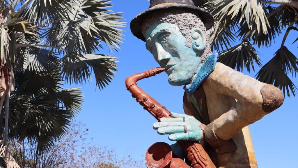 a large statue with a green face plays a saxophone