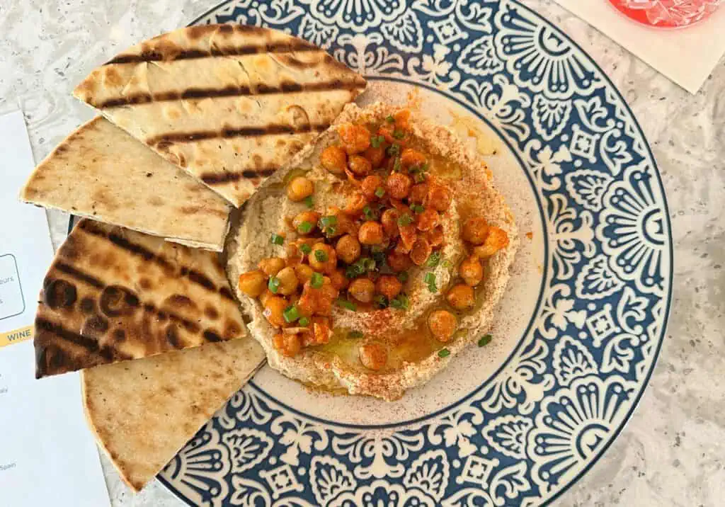 a plate with hummus, chickpeas, and pita
