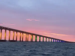 A sunset view of a colorful bridge from the water
