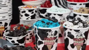 array of different ice cream sundaes in cups with cow print on them.