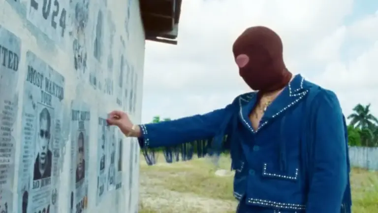 a man in a brown mask examines most wanted signs on the side of a building