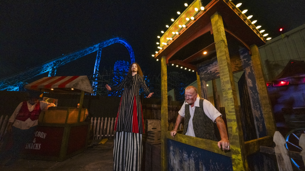a theme park at night with two workers dressed as zombies