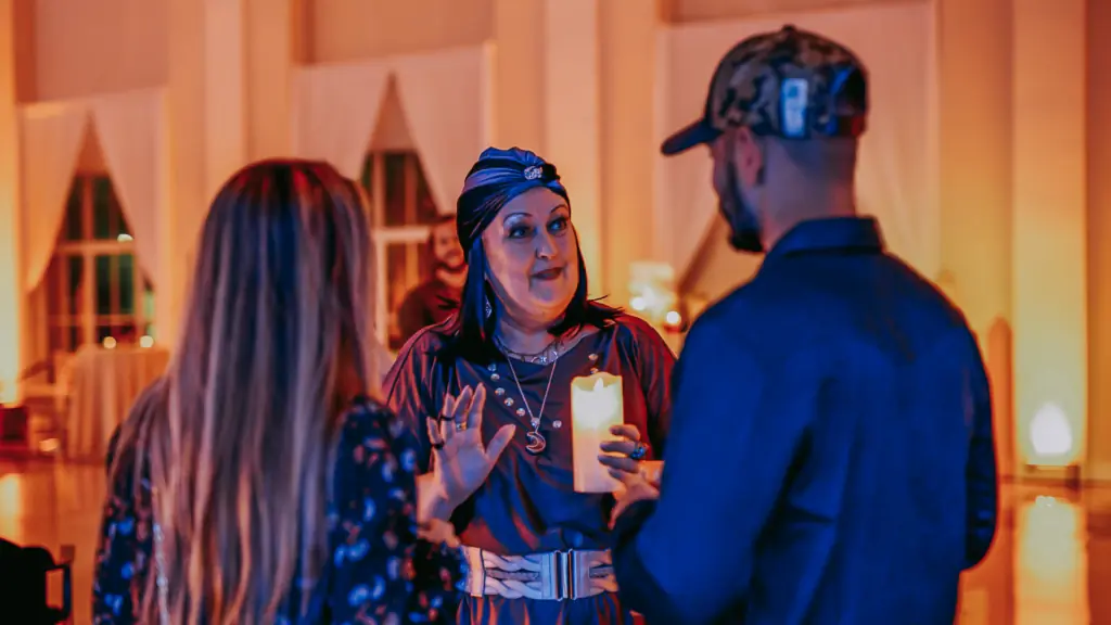 A women dressed as a fortune teller guides guests at a Halloween event