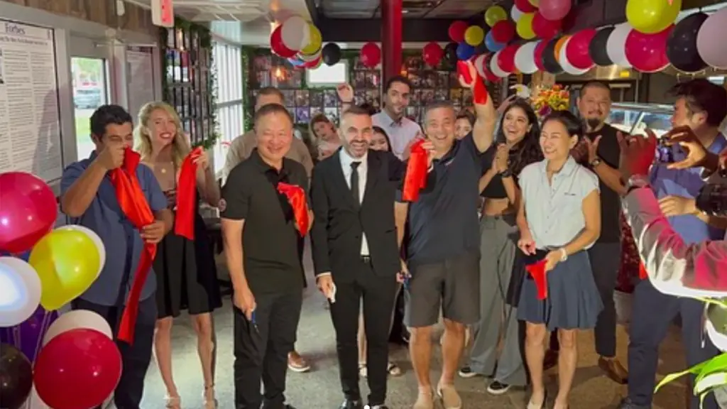 interior of a restaurant with a group of people cutting a ribbon to celebrate its opening