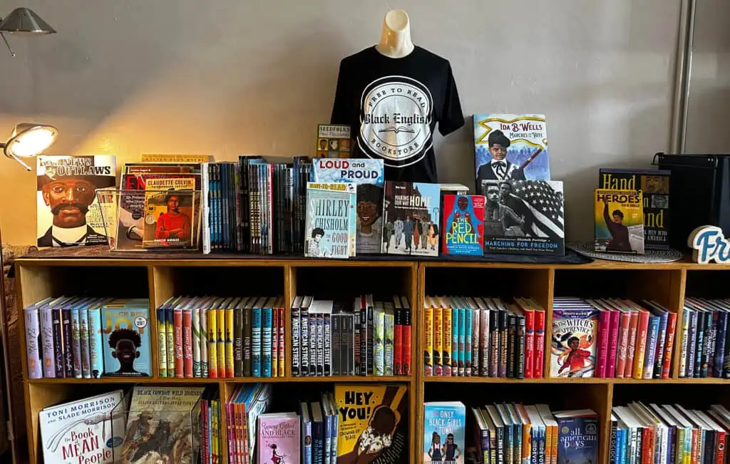 Books arranged on shelves 3 levels up. A mannequin adorns a black t shirt