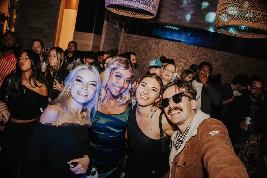 A group of people smile for a photo at a big dance party