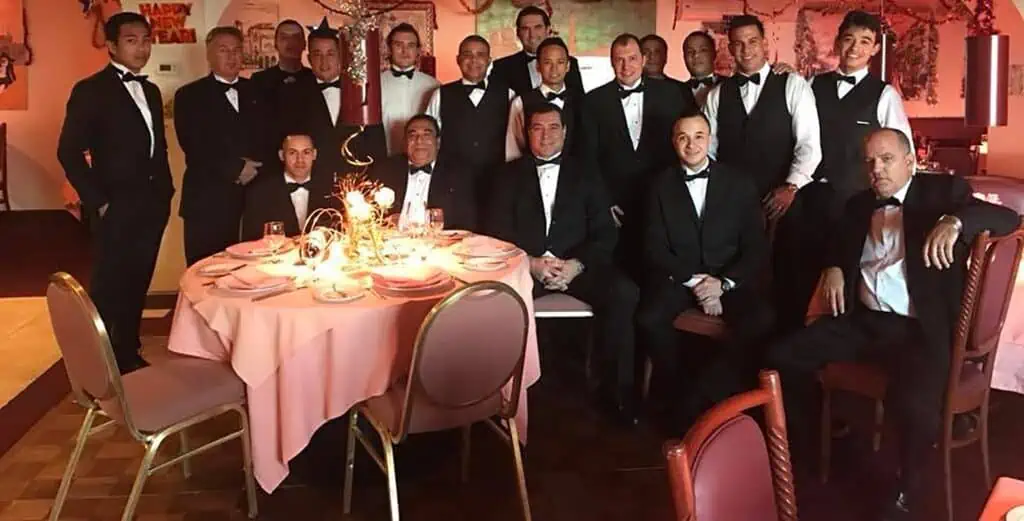 a group of waiters in tuxedo pose at a restaurant