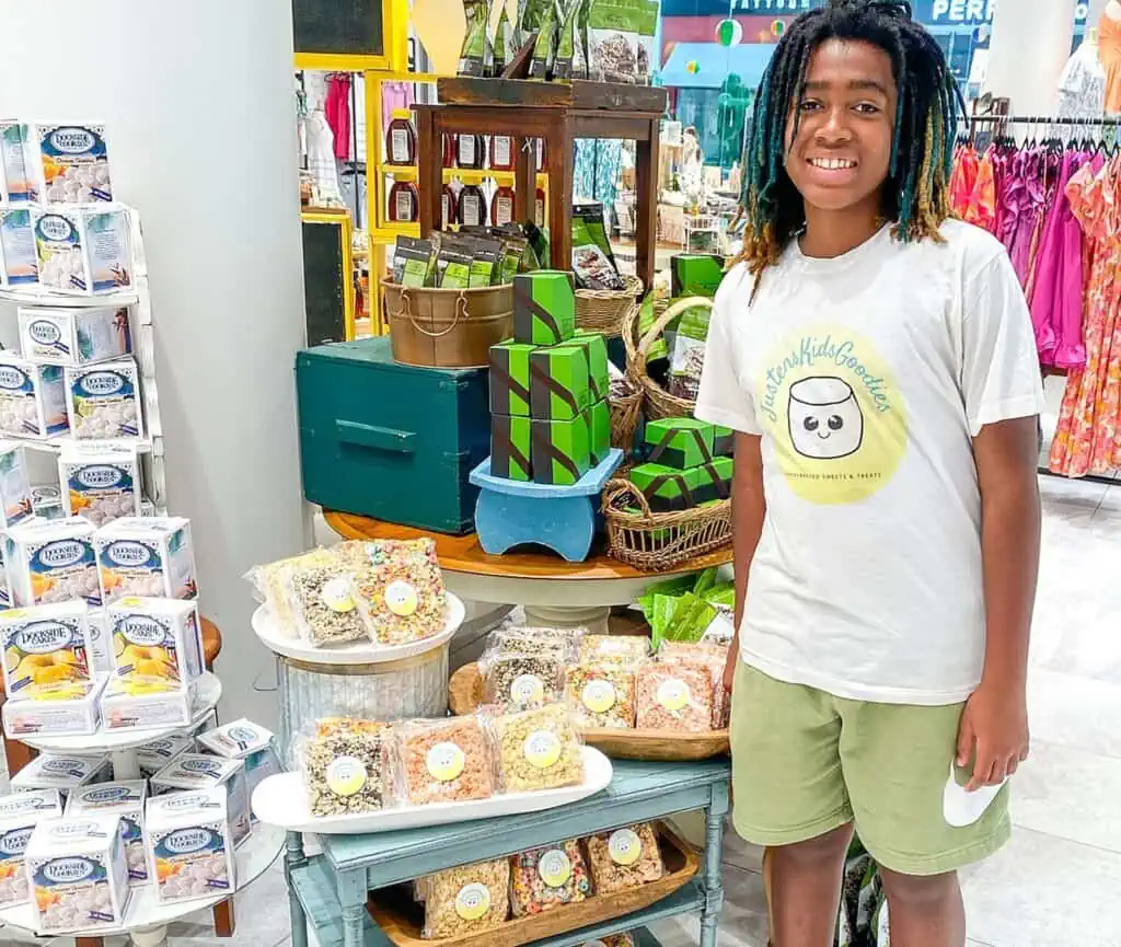 a young business owner stands in front of a table with baked goods he made