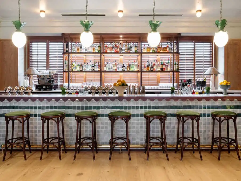 a hotel bar with wooden stools pulled up to a marble counter