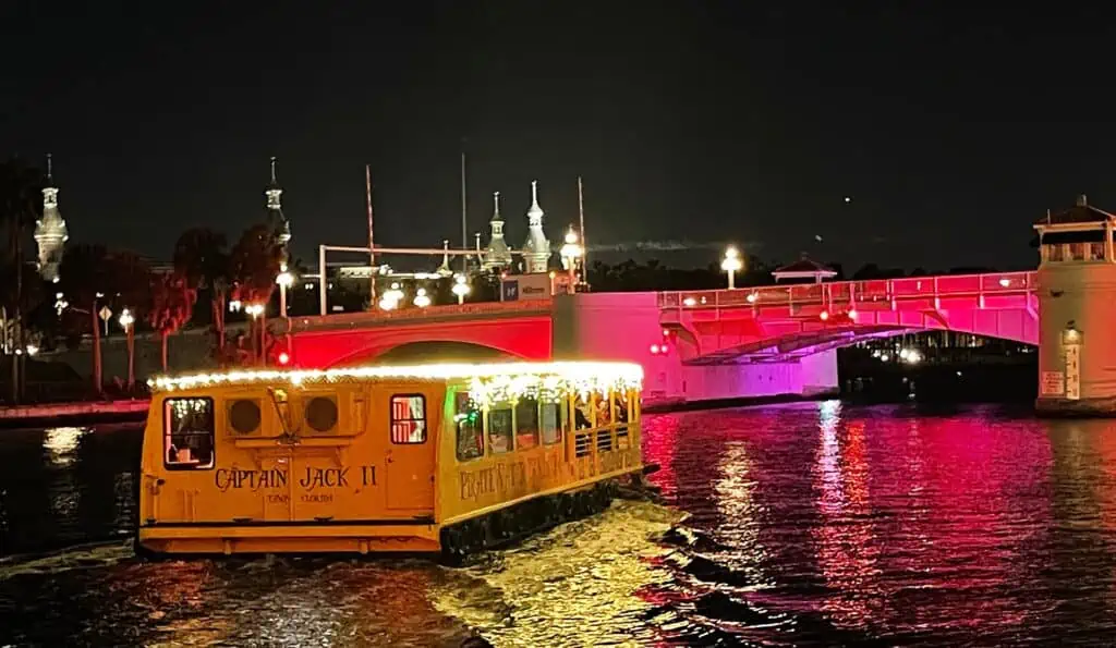 a cruise ship goes under an illuminated bridge