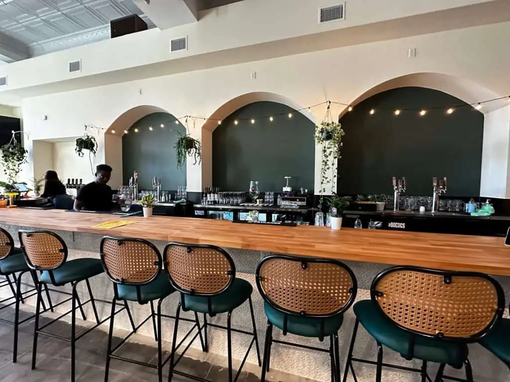 a long bar with wicker bar stools and a green backsplash
