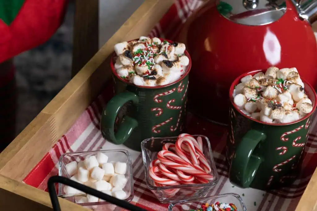 two green mugs filled with hot chocolate and marshmallows 