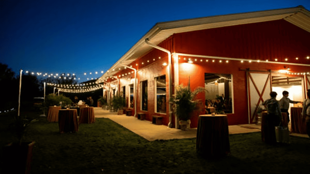 exterior of a red barn with string lights handing over the patio