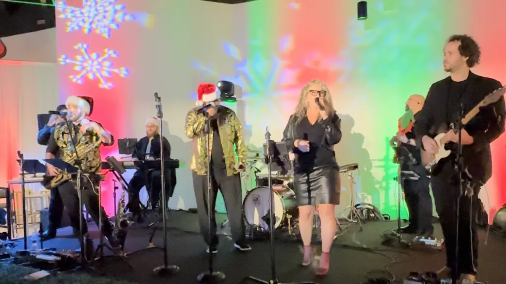 a band performs on stage with Christmas lights behind them.