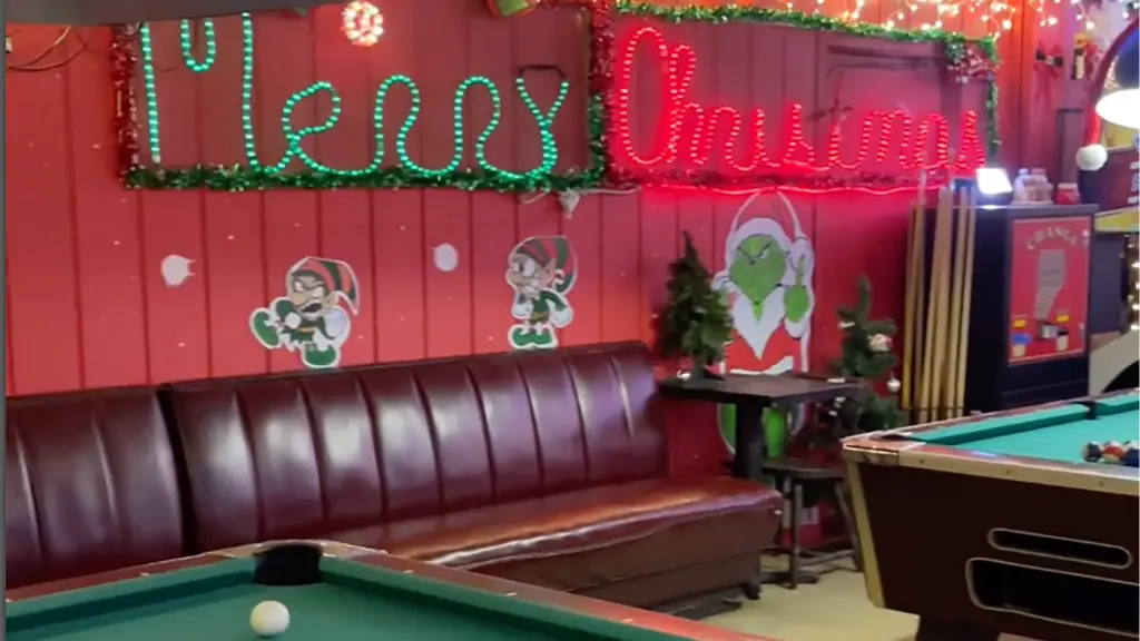 inside a Christmas themed bar with a leather couch and two pool tables