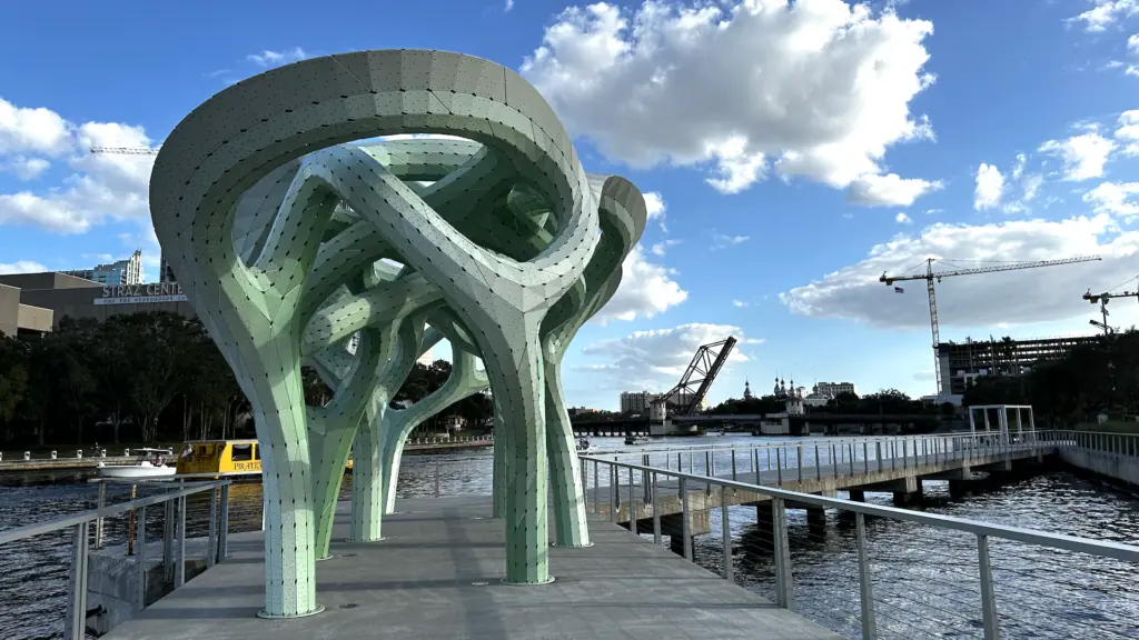 a green arch sculpture on a pier