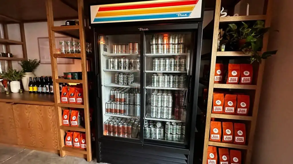 bags of coffee in orange containers, and a refrigerator filled with with wine and beer