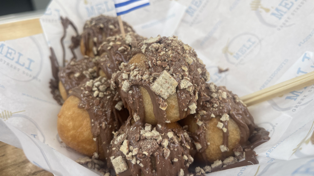 A container filled with chocolate-covered Greek Donuts