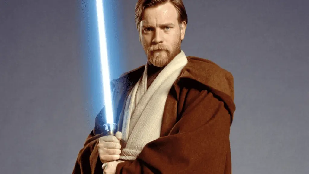 A man in a brown robe holds a blue glowing light saber 