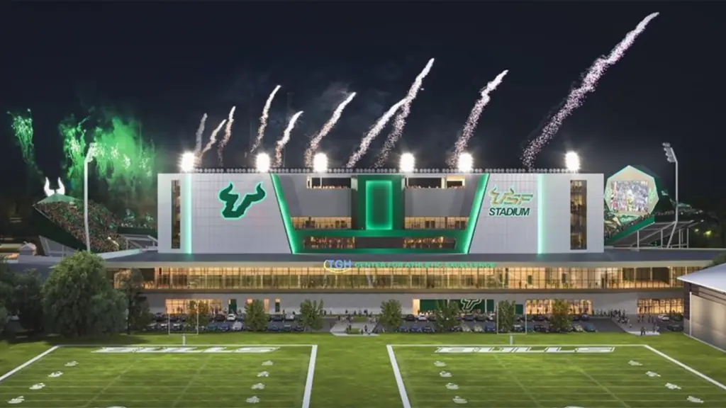 rendering of a college football field with a big athletic center in the background. Fireworks go off in the background. 