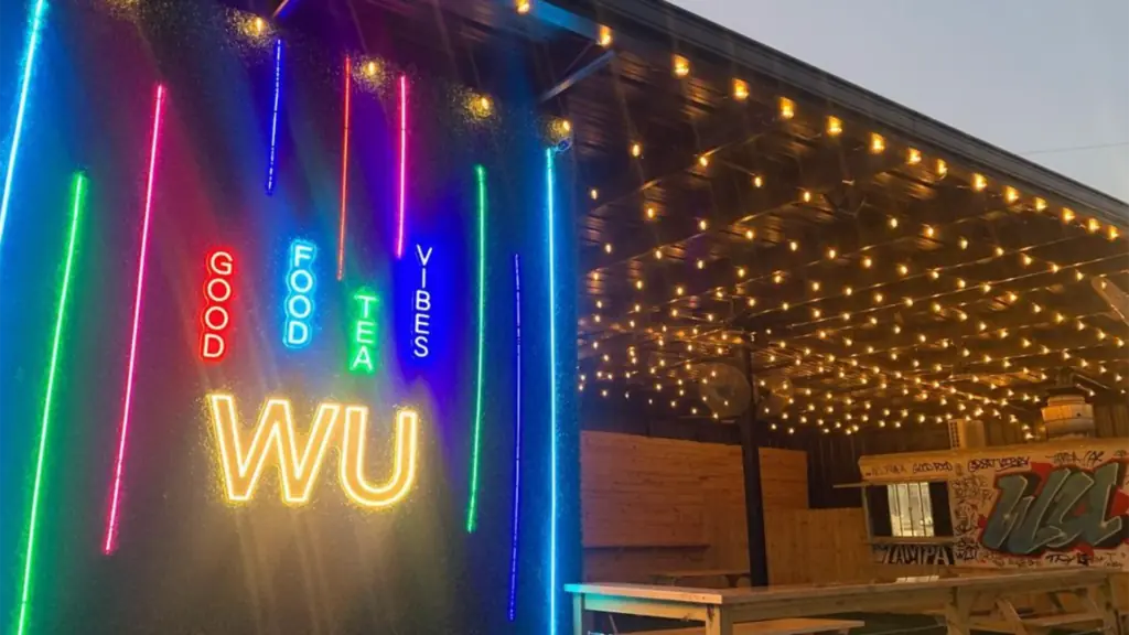 Exterior of a food truck/restaurant with neon lights on an ivy wall