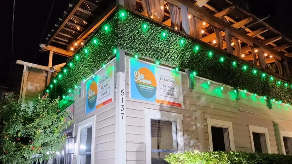 exterior of a restaurant with ivy walls and green lights around the building