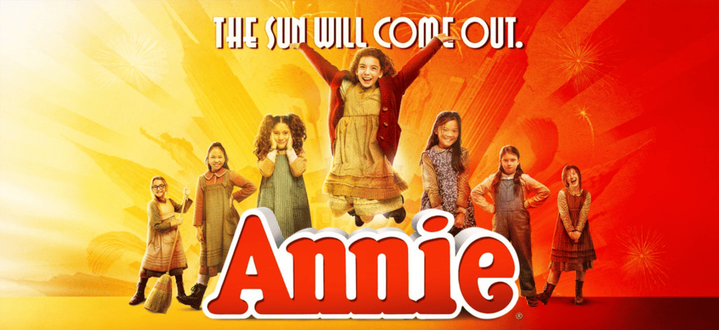 graphic of performers on stage with ANNIE written in big red letters