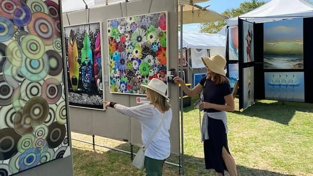Art displayed in park as people browse the tents